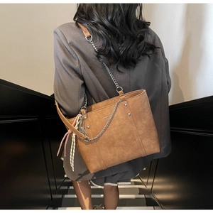 Brown vintage leather tote bag with silver chain strap and decorative woven pendant