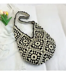 Detail of bohemian black and white crochet flower pattern on a soft knit tote bag