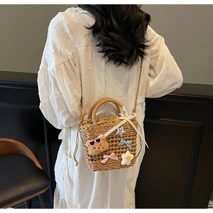 Detail of woven straw bucket bag with teddy bear charm and soft drawstring closure