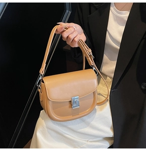 Close-up of light camel saddle bag featuring a silver metal buckle and adjustable strap