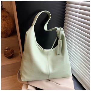 Detail of mint green lychee grain leather tote bag with branded tag on minimalist stone background