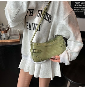 Gros plan du sac à bandoulière riveté vert avocat porté par un mannequin en studio