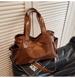 Detail of a large brown faux leather tote bag with stitching and side pockets