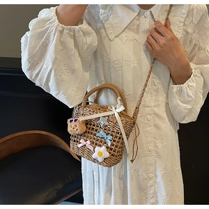 Detail of woven straw bucket bag with cute bear charm and pastel floral embellishments
