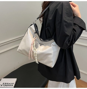 Detail of cream white faux leather tote with silver triangle logo and tassel accent