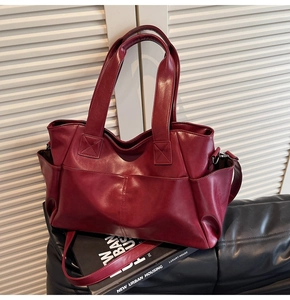 Detail of burgundy tote bag with side pockets, double straps and smooth faux leather finish