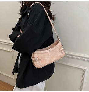 Détail du sac sous l'aisselle en similicuir rose avec rivets argentés et boucle