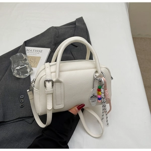 Close-up of white lychee textured boston bag with creative colorful bead charm