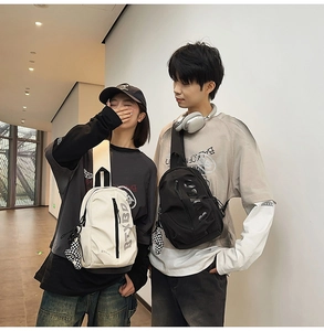 Outdoor street style duo wearing black and beige nylon crossbody chest bags with charms
