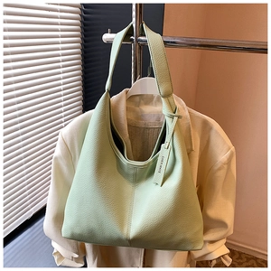 Macro detail of mint green pebble grain leather texture and brand logo tag on tote bag