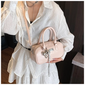Close-up of a pink mini Boston bag with silver bow charm and detachable shoulder strap