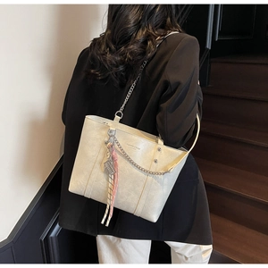 Detail of off-white leather tote bag featuring a decorative scarf and silver chain strap