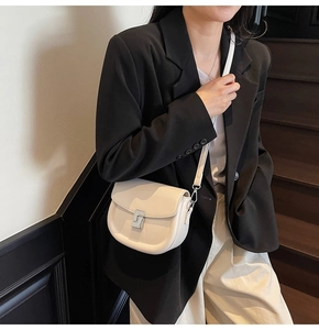 Detail of cream saddle bag with silver buckle worn by model in black blazer