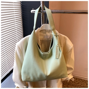 Detail of mint green lychee pattern leather Hobo bag hanging on a minimalist rack