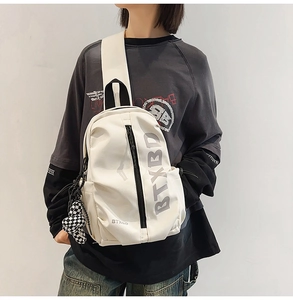 Close-up of white nylon crossbody bag with black checkerboard charm and brand logo