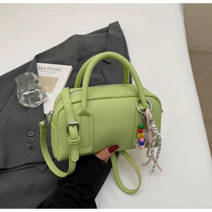 Detail of light green litchi texture pillow bag with colorful beaded charm strap