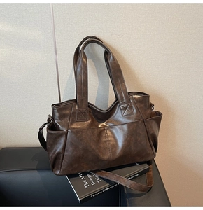 Close-up of brown PU leather tote bag with reinforced handles and detailed X-stitching