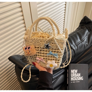 Macro detail of hand-woven straw bucket bag with cute bear and floral charms