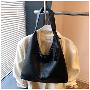 Detail of black pebbled leather hobo bag with wide shoulder strap and brand tag