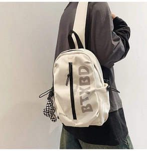 Close-up of minimalist white sling bag with BTXBD logo and checkerboard pendant