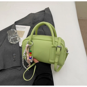 Detail of lime green Boston bag with litchi texture and colorful smiley bead charm