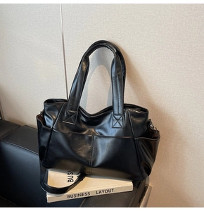 Detail of black matte leather tote bag with X-shaped reinforced stitching on handles