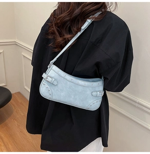Détail du sac bandoulière en similicuir bleu clair avec rivets et boucles style Y2K