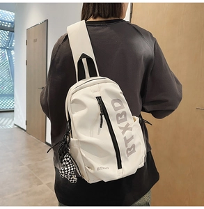 Close-up of white crossbody bag with BTXBD logo and checkered ball pendant on model