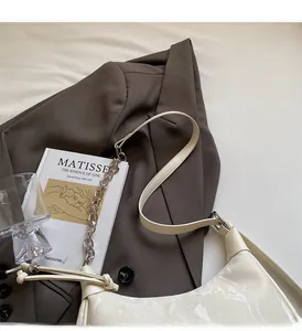 Detail of cream marbled leather dumpling bag with chain strap on a brown blazer