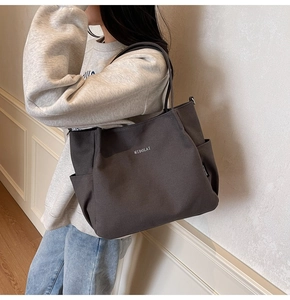 Dettaglio della borsa tote in tela con logo MIDOLAI bianco e tasca laterale funzionale