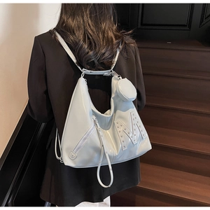 Close-up of light blue patent leather hobo bag featuring rivet letter M and small coin pouch