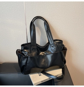 Detail of the black large tote bag with wide shoulder straps and glossy leather finish