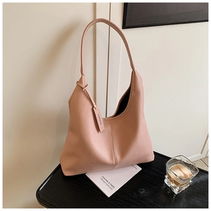 Detail view of pink leather hobo bag with litchi grain texture and branded logo tag