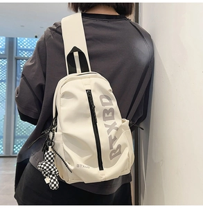 Detailed shot of white chest bag with BTXBD logo and checkered teddy bear charm accessory