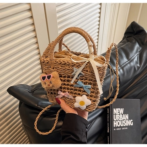 Detail of woven straw bucket bag featuring cute bear charms and a drawstring lining
