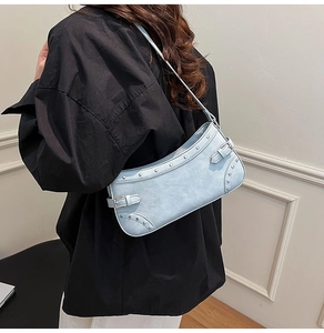 Gros plan d'un sac sous le bras bleu clair avec des rivets et boucles métalliques