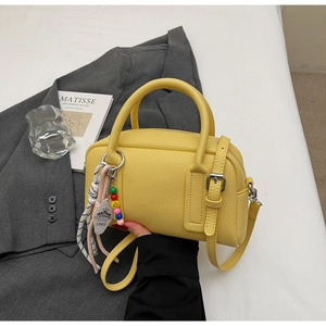 Detail of yellow lychee grain leather handbag with 1865 tag on a grey suit jacket
