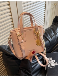 Pink leather bucket handbag with tennis racket charm and crossbody strap for women