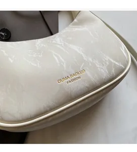 Close-up of marble texture synthetic leather and golden logo on off-white handbag