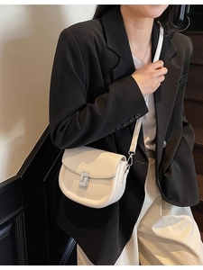 Chic beige saddle crossbody bag for women featuring a minimalist silver buckle closure