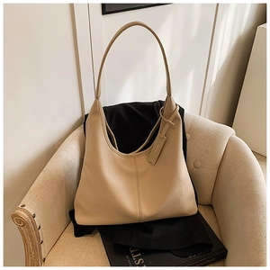 Close-up of beige lychee texture leather hobo bag on a sofa showing premium material grain