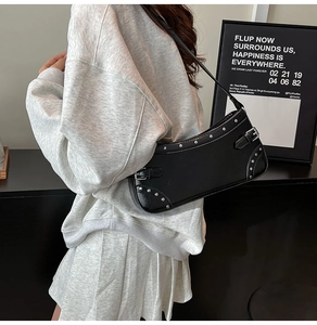 Détails des clous argentés et de la boucle réglable sur le sac à bandoulière en cuir noir