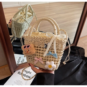 Detail of hand-woven straw bucket bag with cute bear pendant and ribbon decor