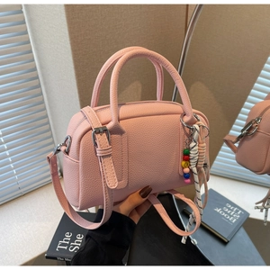 Close-up of pink litchi grain leather mini bag with colorful beaded charm and dual handles