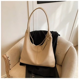 Close-up of beige lychee textured leather tote bag featuring a vertical seam and leather tag