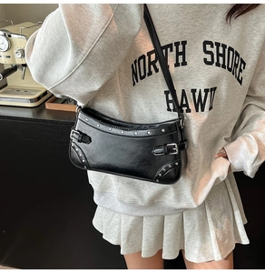 Détails des rivets argentés et des boucles métalliques sur ce sac sous le bras noir
