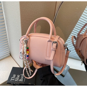 Pink lychee grain leather Boston bag with decorative bead charm and adjustable strap