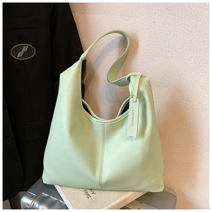 Detail of mint green pebble leather tote bag with brand charm on metal suitcase