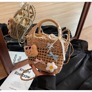 Detail of woven straw bucket bag featuring plush bear charms and floral decorations