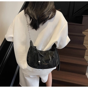 Close-up of the black crescent bag featuring wrinkled texture and silver chain strap details